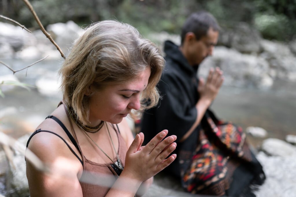 A young couple is meditating with their hands pressed together