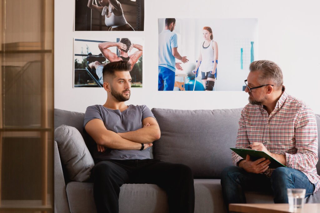 Men in therapy session discussing how Manifest Mindcoach can assist in addiction recovery, PTSD recovery, anxiety, depression, and psilocybin treatment.